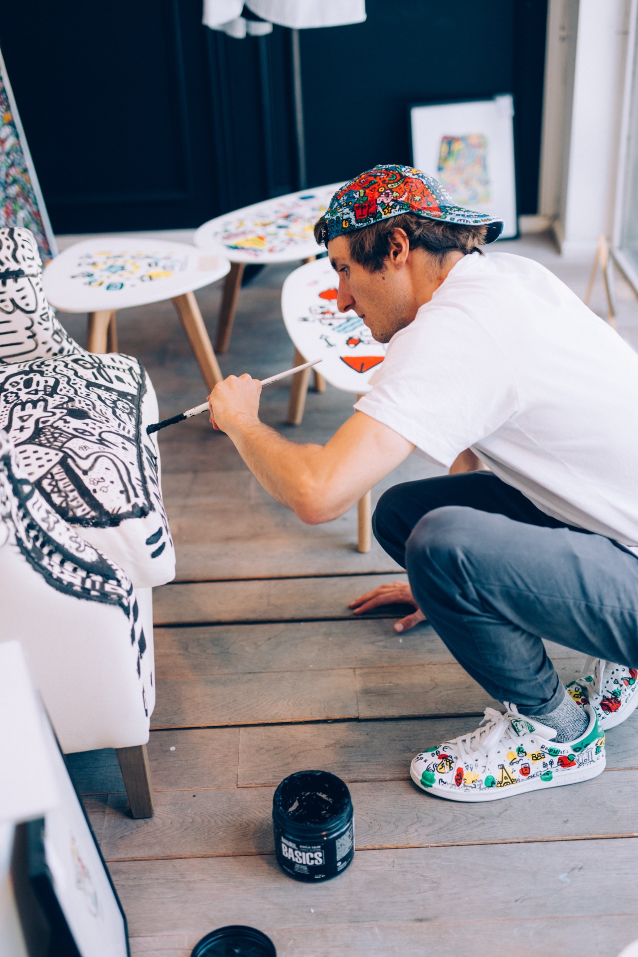 Space Raphaël painting a chair beside illustrated tables