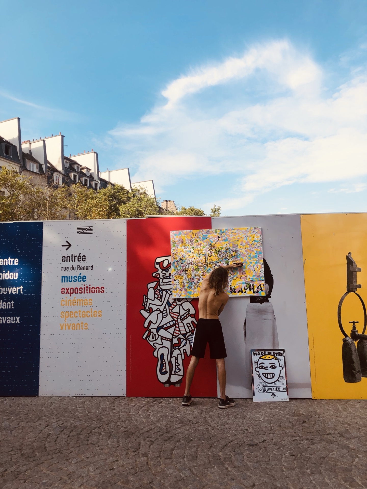 Visual artist Space Raphaël painting outdoors beneath a blue sky